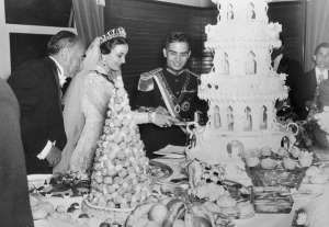 (Original Caption) Photo shows Jordan's King Hussein with his new bride, Queen Dina, at a reception after their recent marriage. the new Queen cuts immense four layer wedding cake as the bridegroom (right) and Sherif Hasan (left), the Queen's uncle, watch.